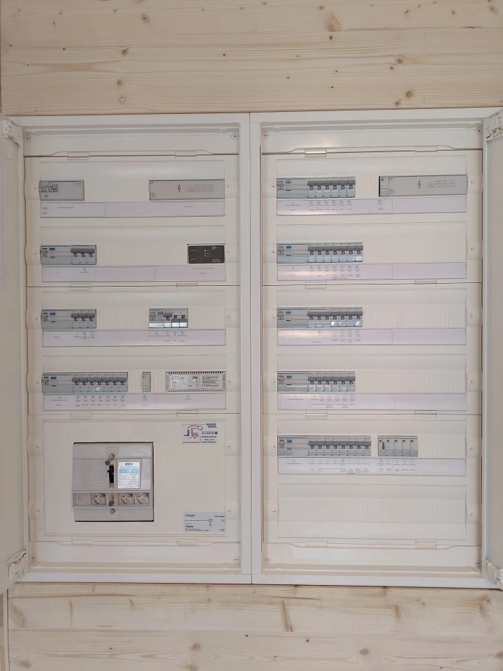 Grand tableau électrique double posé sur un mur en lambris de pin